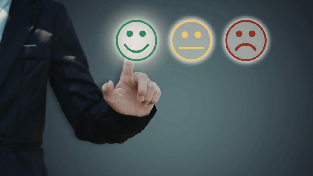 Main d’un homme sélectionnant un smiley vert heureux parmi trois émotions représentant le lien entre émotions et addictions avec LaserAddict Martinique